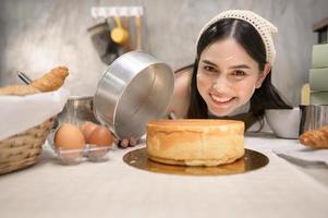 jovem mulher bonita está assando em seu negócio de cozinha, padaria e cafeteria foto