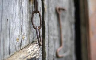 trinco de porta enferrujado velho isolado em uma porta de madeira. fechar-se. painéis desgastados problemáticos. fundo de textura de parede velha. detalhe de uma velha porta de madeira com uma trava de porta enferrujada. foto