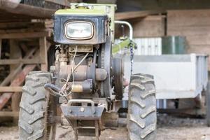 típico trator de passeio a diesel pesado com reboque. equipamento de transporte agrícola do campo. equipamento agrícola portátil, minitrator ambulante. o sistema de partida é mecânico e manual. foto