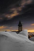 igreja da montanha no meio da noite coberta de neve foto