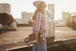 mulher segurando skate no pôr do sol foto
