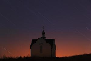 vestígios das estrelas no céu noturno sobre igreja ortodoxa foto