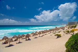guarda-chuvas em uma praia de areia com água azul em um dia ensolarado perto de cancun, méxico foto