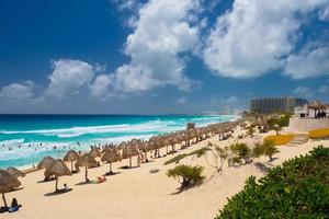 guarda-chuvas em uma praia de areia com água azul em um dia ensolarado perto de cancun, méxico foto