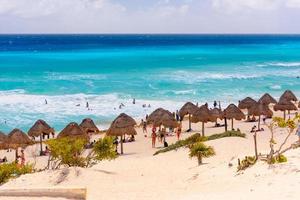 guarda-chuvas em uma praia de areia com água azul em um dia ensolarado perto de cancun, méxico foto