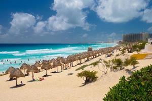 guarda-chuvas em uma praia de areia com água azul em um dia ensolarado perto de cancun, méxico foto