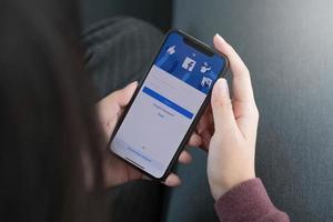 mulher segurando um iphone x com facebook de serviço de internet social na tela. foto