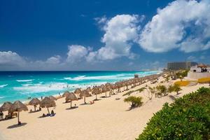 guarda-chuvas em uma praia de areia com água azul em um dia ensolarado perto de cancun, méxico foto