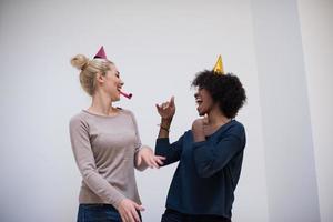 mulheres sorridentes em bonés de festa soprando apitos foto