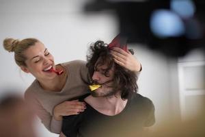 casal em chapéus de festa soprando no apito foto