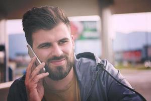 homem de negócios casual jovem bonito com barba usando telefone celular foto