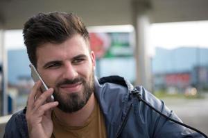 homem de negócios casual jovem bonito com barba usando telefone celular foto