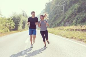 jovem casal correndo ao longo de uma estrada rural foto