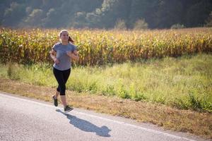 mulher correndo ao longo de uma estrada rural foto