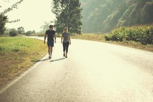 jovem casal correndo ao longo de uma estrada rural foto