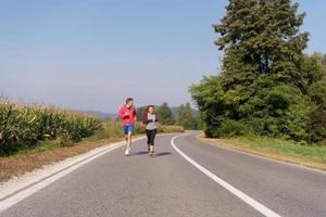 jovem casal correndo ao longo de uma estrada rural foto