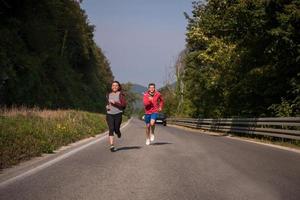 jovem casal correndo ao longo de uma estrada rural foto
