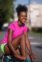 mulher afro-americana corredor apertando cadarço de sapato foto