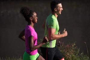 jovem casal multiétnico sorridente correndo na cidade foto