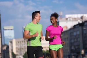 jovem casal multiétnico sorridente correndo na cidade foto