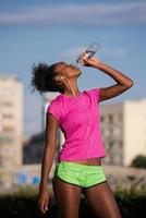 mulher afro-americana bebendo água depois de correr foto