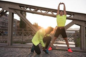 casal de jogging aquecendo e esticando na cidade foto