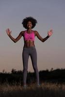 mulher negra está fazendo exercícios de alongamento relaxando e aquecendo foto