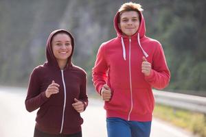 jovem casal correndo ao longo de uma estrada rural foto