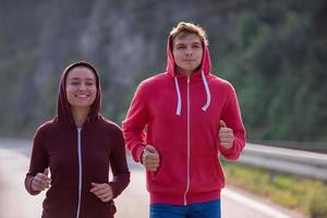 jovem casal correndo ao longo de uma estrada rural foto