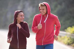 jovem casal correndo ao longo de uma estrada rural foto