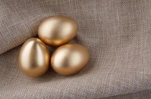 três ovos de ouro em um fundo de tecido. foto