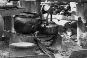 chaleira de metal. a água fervente à moda antiga usa lenha para fazer fogo. Preto e branco. foto