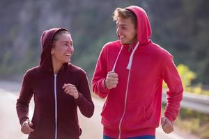 jovem casal correndo ao longo de uma estrada rural foto