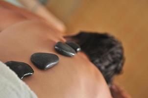 mulher bonita tem massagem hotstone no spa e centro de bem-estar foto