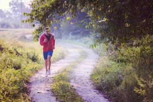 homem correndo ao longo de uma estrada rural foto