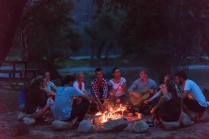 jovens amigos relaxando ao redor da fogueira foto