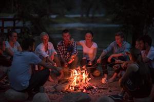 jovens amigos relaxando ao redor da fogueira foto