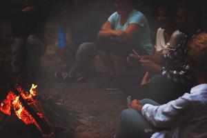 jovens amigos relaxando ao redor da fogueira foto