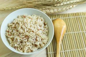 arroz integral em tigela branca na mesa de madeira para conteúdo de alimentos saudáveis. foto