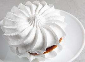 lindos merengues brancos em um prato branco. bolo branco. foto