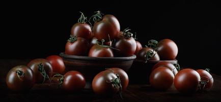 muitos tomates suculentos maduros em um fundo preto. tomates cuma. foto