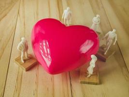 coração rosa e figura branca na mesa de madeira para saúde, conteúdo médico. foto