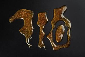 710 letras resina de cera de cannabis dourada em fundo escuro foto