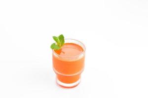 um copo de suco de cenoura fresco, muito bom para a saúde. servido em vidro no fundo branco foto
