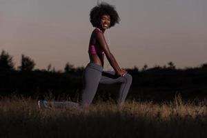 mulher negra está fazendo exercícios de alongamento relaxando e aquecendo foto