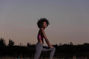 mulher negra está fazendo exercícios de alongamento relaxando e aquecendo foto
