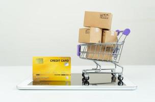 caixas de papel em um carrinho com tablet em fundo branco, compras on-line ou conceito de comércio eletrônico foto