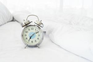 close-up vista do despertador de manhã em uma cama branca, conceito de despertar foto