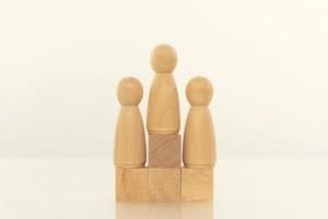conceito de liderança. modelo de pessoa de madeira entre pessoas em fundo branco. foto