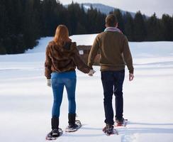 casal se divertindo e andando com sapatos de neve foto